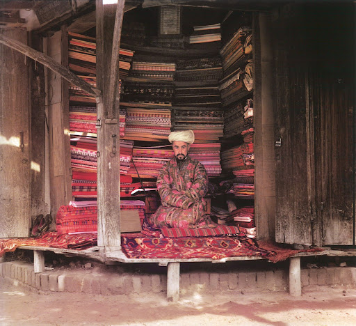 This photograph from the Library of Congress, focuses on a fabric merchant in Samarkand, surrounded by brightly colored merchandise. This photograph from the Library of Congress, focuses on a fabric merchant in Samarkand, surrounded by brightly colored merchandise.