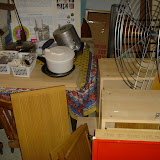The cabinets and various kitchen items in their temporary basement home. There are also lots of dishes, etc. in boxes in the living room