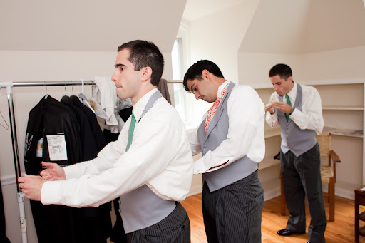 the three brothers help each other with their vests.