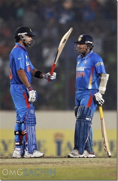 Sachin Tendulkar, right, watches as teammate Virat Kohli raises his bat © AP Photo