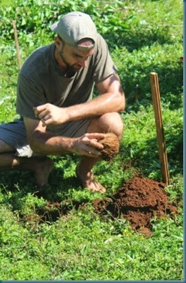 Aaron scraping dirt with coconut shell