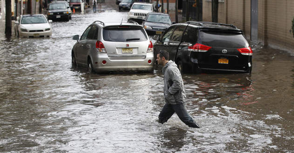 A man walks along the street as 2 automobiles are caught in the waters as the rescue by the National Guard continues after Hurricane Sandy Hoboken, New Jersey, 31 October 2012. Photo: William Perlman / The Star-Ledger