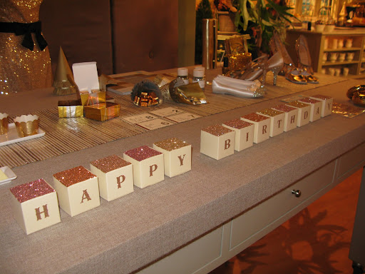 Glittered Letter boxes spelling out Happy Birthday. 
The Classic Cube boxes from B.T. elements, www.btelements.com

-         MS Crafts Copper Glittered Alphabet Letters from www.michaels.com for stores) There is enough in a package to spell Happy Birthday!

Fine glitter, by Martha Stewart Crafts, www.michaels.com for stores