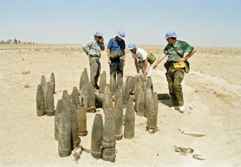 Members of the UNSCOM team inspect mustard agent l55-mm artillery projectiles, damaged by fire, at the Fallujah Chemical Proving Ground, 01 August 1991. From left to right, the inspectors are; John Griffin (USA), Bernhard Brunner (Switzerland), Johan Santesson (WHO), and Igor Mitrokhin (USSR). UN Photo / Shankar Kunhambu / Iraq Photo # 65375