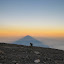 Hiker reaches summit as Semeru casts a shadow at sunrise