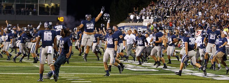 Utah State players storm the field after beating the University of Utah in Logan