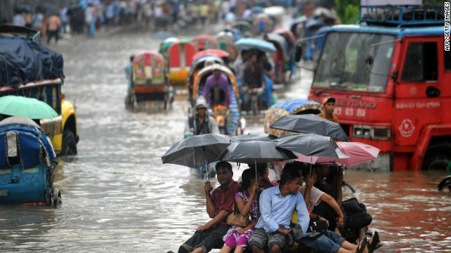 Bangladeshi pedestrians holding umbrellas hitch a ride on a rickshaw van as they attempt to stay dry over flood waters in the Bangladeshi capital of Dhaka on 28 July 2009. The Met Office study predicts that, over the course of the century, an additional five million people in Bangladesh will be displaced by floods caused by climate change. CNN