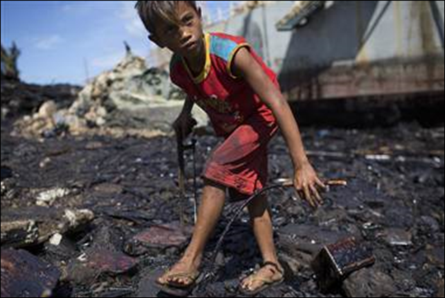 Despite thick oil slicking his hands, 14-year-old Giray Boreros uses a hacksaw Friday to collect scrap iron in the devastated fishing town of Estancia, Philippines. Typhoon Haiyan hit here with such force that a barge ran aground, spilling approximately 1.4 million liters of oil into the bay, according to the town's mayor. Photo: Jim Seida / NBC News