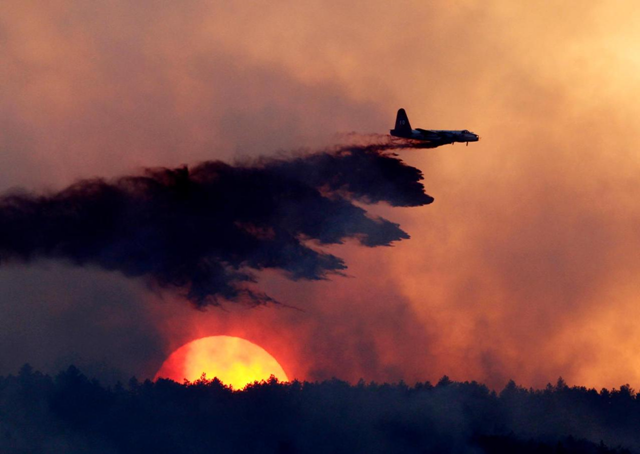 In this 12 September 2010 file photo, a slurry bomber drops retardant on a burning ridge as the sun sets behind it as a wildfire burns near Loveland, Colo. The West's 2012 wildfire season exploded in earnest last month with a wind-whipped blaze that killed three people in rugged alpine canyon country near Denver. At its peak, it took a 700-strong federal firefighting team a week of labor, day and night, to tame the blaze, and other states throughout the West took notice. Ed Andrieski / AP Photo