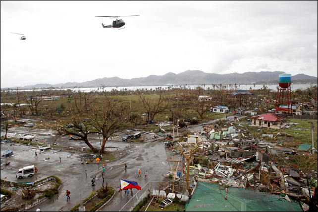 Helicopters hover over the damaged area after super Typhoon Haiyan battered Tacloban city, central Philippines, 9 November 2013. Photo: Romeo Ranoco / REUTERS