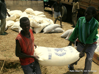 Deux  hommes  transportent  un  sac  de vivre en provenance d'un convoi du  Programme Alimentaire Mondial(PAM)  ce 1/01/2003 dans le Camp des déplacés à Geti en RDC, lors de la visite de Jan Egland, Secrétaire générale des Nations Unies en charge des affaires Humanitaire. Radio Okapi/ Ph. John Bompengo