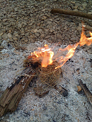 Using the half-burnt logs from the previous nights fire to get it going again - a spark from a firesteel and a bit of blowing till it glows, then drop on some dry grass and it's away...