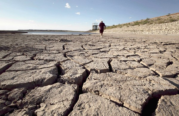 Eddie Ray Roberts, superintendent of the water and waste department in Robert Lee, Texas, walks the dry bed of Lake E.V. Spence on his way to check a water pump, 3 October 2011. Each day he checks the pump, which feeds a reservoir. Tony Gutierrez / Associated Press