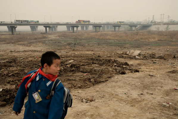 A boy heading back home from school walked by the dry riverbed of the Yongding River in north China. Credit: Gilles Sabrie for The New York Times