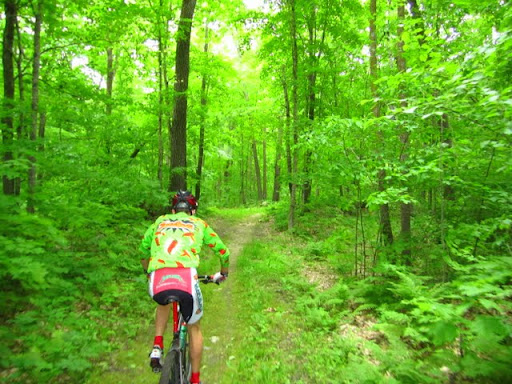 Riding on Rootin Tootin trail, part of the Laddies Loppet mountain bike course. Woods are lush.