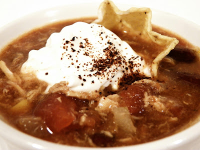 Slow cooker chicken tortilla soup - garnished with sour cream, a tortilla chip, and a sprinkle of chili powder