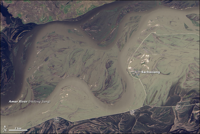 The Landsat 8 satellite acquired this image on 27 September 2013. The Amur River, swollen by record rainfall, has swallowed up the Chinese town of Bachaxiang, having overcome the straight white levee that stands between the town and the river's usual channels. Photo: Jesse Allen and Robert Simmon, using Landsat data from the USGS