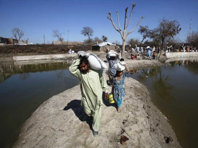 Pakistan flood victims carry supplies. 'US$600 million is still needed to support early recovery activities': UN Emergency Relief Coordinator Valerie Amos. PHOTO: REUTERS / FILE
