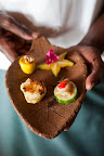 The chef holds a combination platter of star anise, local fish, scallops, and a vegetable blend.