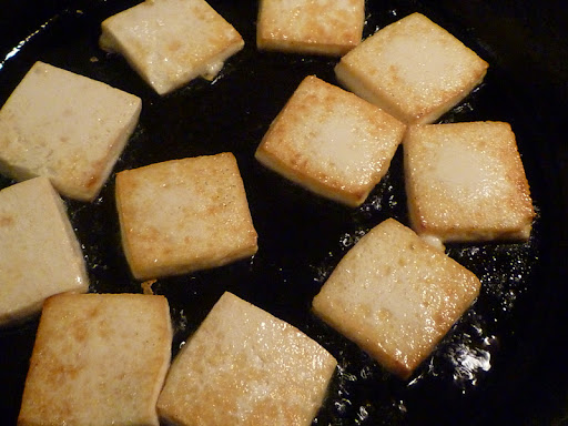 Tofu crisping up in a cast iron skillet