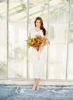 A punchy orange bouquet pops against a white dress. The loose arrangement highlights the dress's streamlined silhouette.