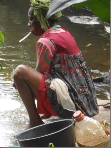 Lady washing dishes in river Kribi