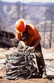 The Dirty Hands People - A logger ties down a bundle of choker cables moments before they were picked up by a Columbia Helicopter working on the White Mountain Apache Reservation following the 2002 Rodeo-Chediski Fire. These cables are used to lift bundles of logs which the helicopters then fly to log landings where they are loaded on trucks - in this case for delivery to Union Pacific Railroad sidings in Globe and Snowflake.