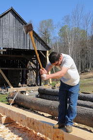 Seth Kelley scores the timber with a felling axe before making a final pass with the broad axe