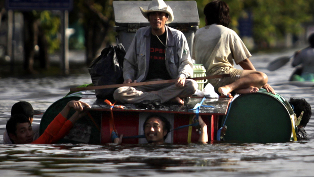 Thai men use makeshift boats to leave a flooded area in Bangkok, 26 October 2011. AP Photo