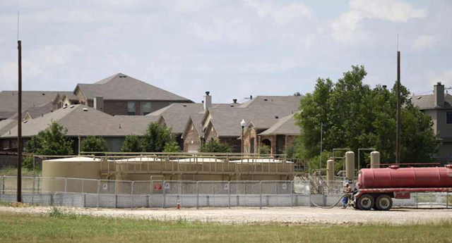 Natural gas well holding tanks sit next to a subdivision of homes in Denton, Texas, Thursday, 29 May 2014. This North Texas city wants less gas and more hot sauce. Unlike most Texas communities that have embraced the lucrative oil and natural gas booms, Denton leaders are considering a petition to ban hydraulic fracturing and are trying to persuade Sriracha to move its massive pepper-grinding operations from California. Although sitting on top of the Barnett Shale, believed to hold one of the largest natural gas reserves in the U.S., Denton would rather be known for having the largest community garden in the U.S. Photo: LM Otero / AP