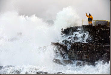 A-man-signals-as-waves-crash-against-the-shore-at-Portstewart-in-northern-Ireland-December-10-2014