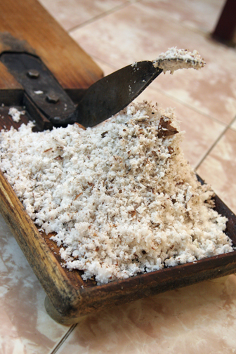 The coconut is grated on a traditional grater board.