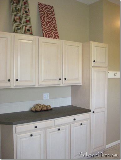 Maple cabinets, brown counter tops, red fabric wall art, beige walls, white woodwork