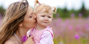 Mother kissing daughter in meadow outdoor