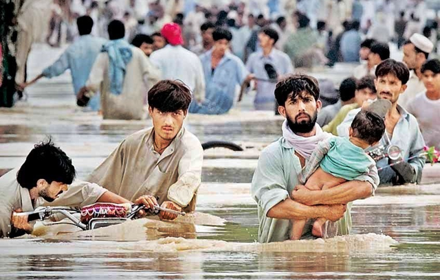 Survivors wade through floodwaters in Pakistan, July 2010. stockmarkettoday.in
