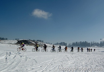Tourists cycle on the snowy slopes of Gulmarg