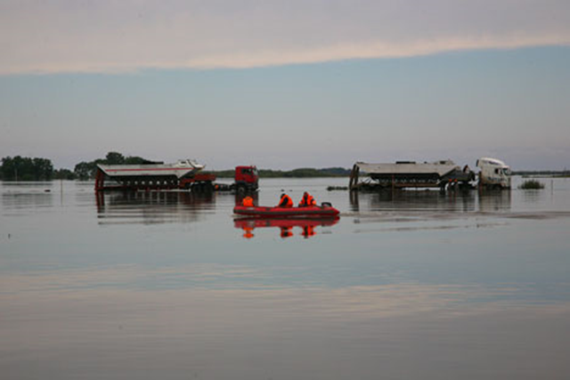 Residents of Russia's Far East steer an inflatable raft over floodwaters in the Amur River. In September 2013, over 60 communities with a combined population of almost 36,000 stll remained in the flood zone. Photo: RIA Novosti