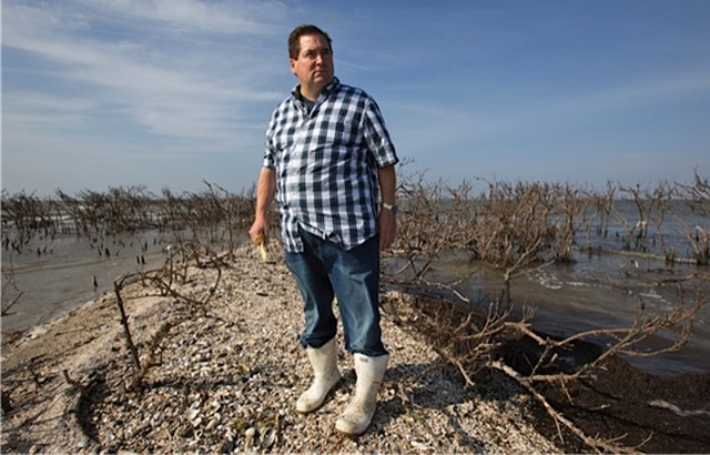 Billy Nungesser, president of Plaquemines Parish, Louisiana, stands on what remains of Cat Island, holding pelican bones, 18 April 2013. Three years after the BP Deepwater Horizon disaster, tar balls and oil sheen blight Gulf Coast. Photo: Julie Dermansky / The Atlantic