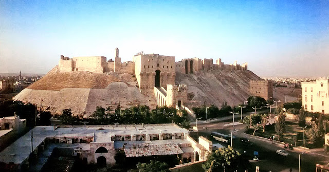 The Citadel at Aleppo. The Citadel at Aleppo. The most imposing building in Aleppo is the medieval Citadel, which rises high above the city.This natural, flat-topped mound was used in pre-lslamic times as a settlement and place of worship.The Ayyubid ruler al-Malik al-Zahir Ghazi (1186-1216) strengthened it into one of the best fortified military bases in Syria. He had a deep moat dug round the mound and filled with water, and built an imposing new entrance, which was flanked by two massive rectangular towers and could only be reached over a multiple-arch bridge. The Citadel was heavily renovated during the Mamluk period.The most significant addition was a sumptuous ceremonial hall, which the Mamluk governor Jakam min Iwad had built above the Ayyubid gate in 1406/07.