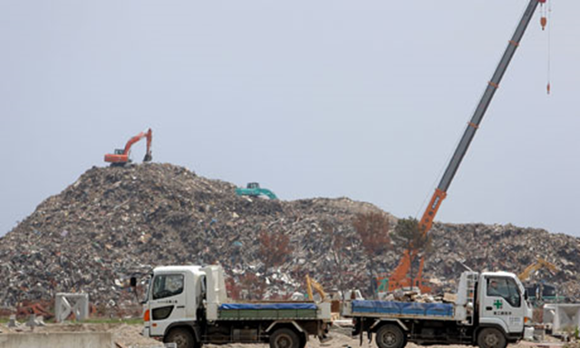 Fukushima nuclear disaster: Trucks drive past piles of rubble collected after the tsunami and nuclear disaster. Kiyoshi Ota / Getty Images / guardian.co.uk