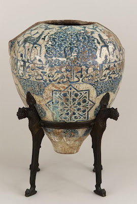 The Alhambra Vase | Origin:  Spain | Period: late 14th-early 15th century  Nasrid period | Details:  Mariano Fortuny, the famed textile and costume designer, bought the Freer Vase from a tavern in Granada. The bronze stand, inspired by the Fountain of the Lions at the Alhambra, was designed by Fortuny. The vase is missing its collar, neck, winglike handles, and lustered surface, but is a close cousin to other surviving Alhambra vases, including the vase known as the Alhambra Vase, now in the Museo de la Alhambra in Granada. Its present state only hints at its former appearance, as it must have been among the most magnificent of all of the late Alhambra vases. Its pleasing proportions are accentuated by the placement of an inscription band at its widest point; the contents of the inscription are unique among these vases. This inscription is autonomous, in that, it makes the vase speak in the first person. Like the inscription on the pyxis and other inscriptions that survive in stucco at the Alhambra palace, this one asks the viewer to contemplate the beauty of the object and its setting.   Inscriptions : Deer: Good health; Roundels: Good health. Central band: O thou onlooker who art adorned with the splendor of the dwelling / Look at my shape today and contemplate: thou wilt see my excellence / For I appear to be made of silver and my clothing from blossoms / My happiness lies in the hands of he who is my owner, underneath the canopy . | Type: Earthenware painted over glaze | Size: H: 77.2  W: 68.2  cm | Museum Code: F1903.206a-b | Photograph and description taken from Freer and the Sackler (Smithsonian) Museums.