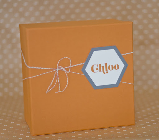 Covered in palette-matching paper and tied with gray and white baker's twine and a hexagonal tag, this gift box is the perfect thing to hold your bridesmaids' presents.