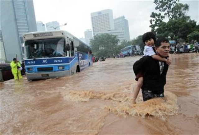 A man carries his son across a flooded area at the business district in Jakarta, 17 January 2013. Photo: REUTERS / Supri
