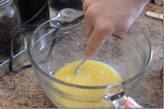 a woman stirring an egg mixture in a glass mixing bowl