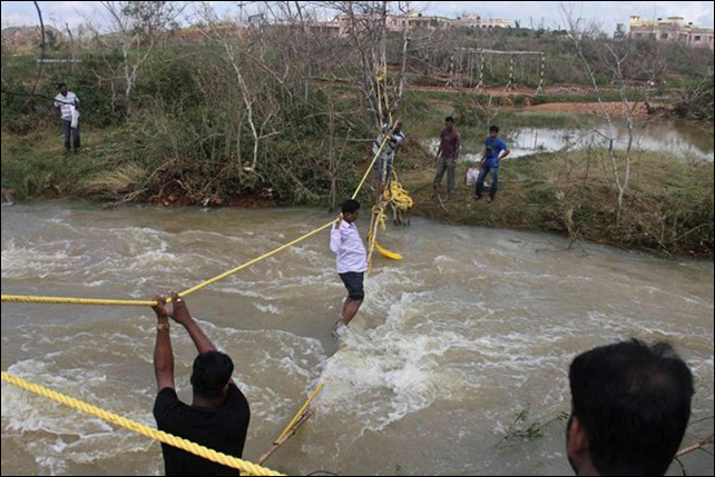 People use a rope bridge to cross floodwaters on 26 October 2013 in Ganjam district in eastern India. Photo: Reuters