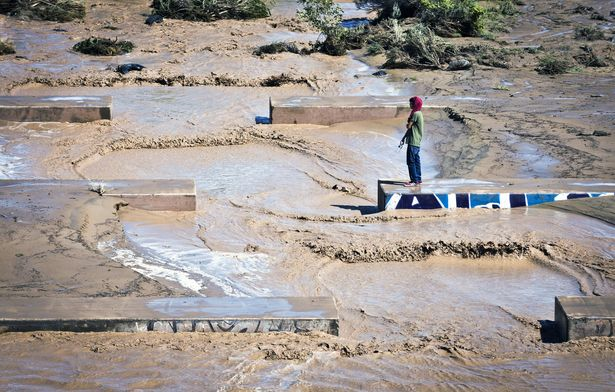 Christian Baste, of Albuquerque takes a walk alongside the flowing waters moving through the Swinburne Dam on the westside of Albuquerque, New Mexico, on Friday, 13 September 2013. Previously drought-stricken rivers surged their banks across New Mexico on Friday, closing roads, stranding children at schools and forcing evacuation from Las Vegas to Truth or Consequences from 'life-threatening' floods. Photo: Marla Brose / The Albuquerque Journal