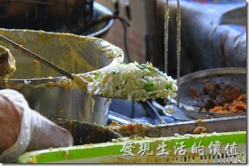 台南東興蚵嗲的製做過程。先在鏟子上裹上一層麵皮，然後放在高麗菜、豆芽、芹菜及韭菜等配菜，然後才放上鮮蚵，最後在淋上麵皮把整個蚵嗲包起來，抹平後下油鍋油炸。