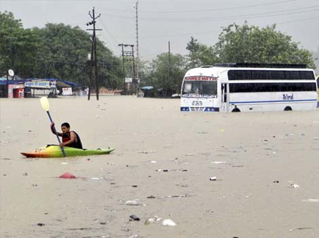 A man rows past a bus partly submerged in flood water in Rishikesh, Uttarakhand, 20 June 2013. Photo: AP
