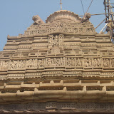 In the middle niche is shown Mahishasurmardini, slaying demon in buffalo form. Her one foot is placed firmly on the demon's back and by one hand she has held the head of the buffalo demon. Her trisula is piercing through the body of demon. On her left is shown Bhairava? naked, holding a munda (human skull) and a banner. On her right is non-identifiable figure. Other niches on either side show common people as dancers, musicians and couples. Above this tier, on central niche, is a figure of Kali carrying a munda (human skull), parasu and khatvanga.