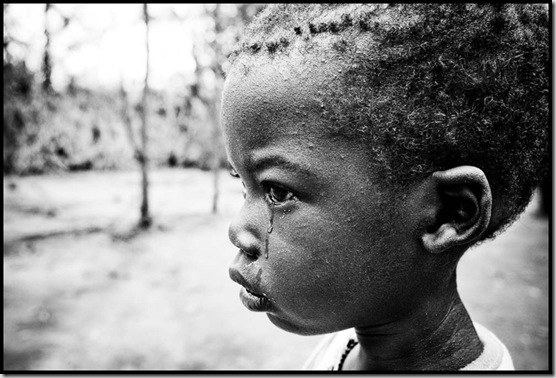 A young boy cries in front of an IRC feeding center as food rations are given out to refugees suffering from famine and drought.  Kakuma Refugee Camp, Kenya.